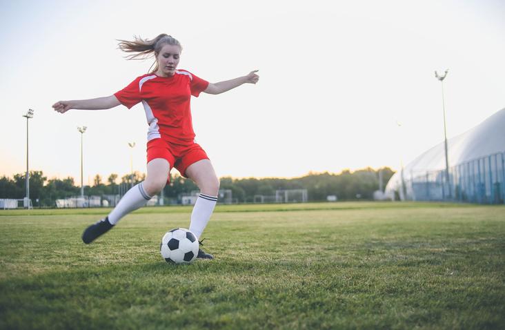 young woman playing soccer on field