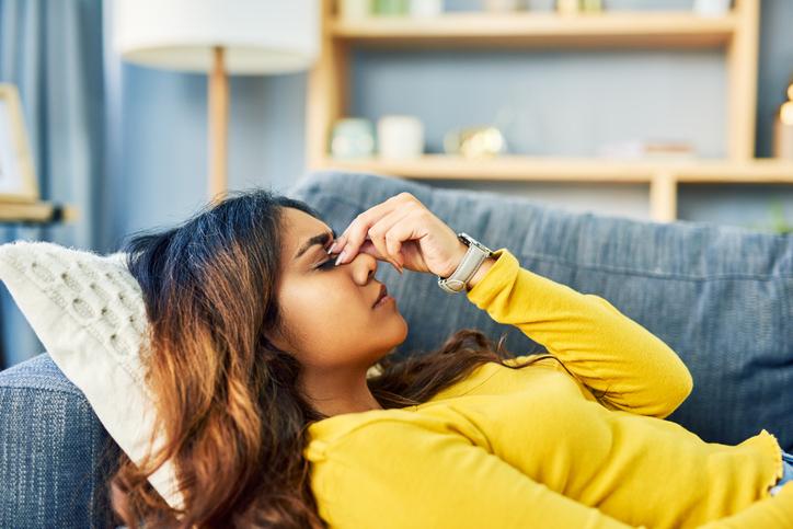 woman laying down on couch with head pain