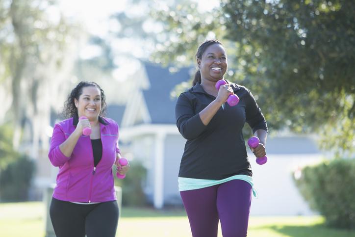 two woman exercising out with hand weights