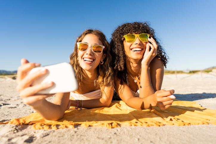 two women at beach taking selfie