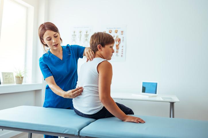 healthcare professional looking at young boy's back