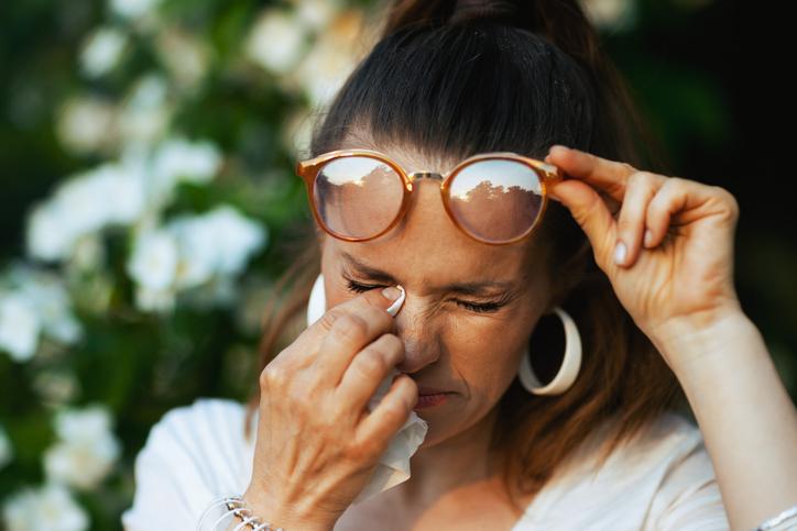 woman rubbing eye with tissue