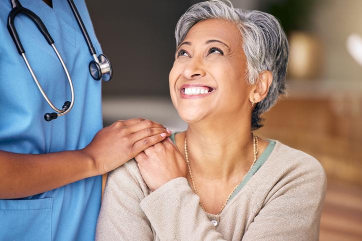 health care professional putting hand on woman smiling