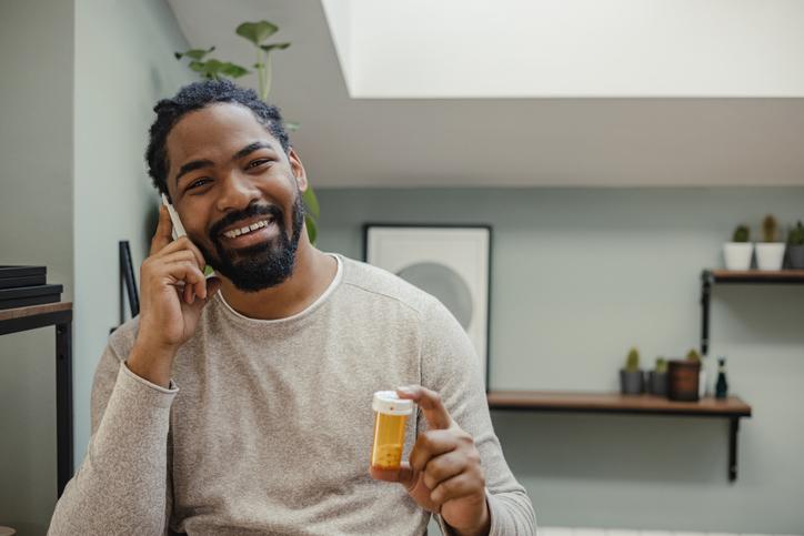 man on phone holding pill bottle