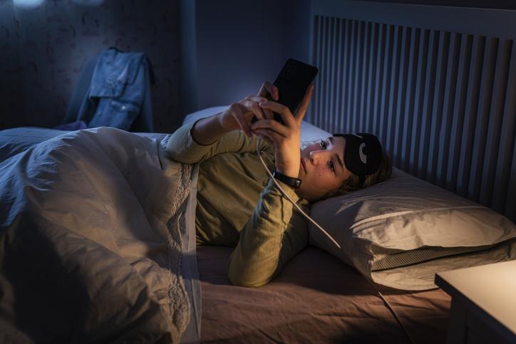 young woman looking at cell phone in bed