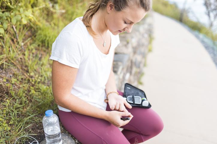 young woman checking insulin outside