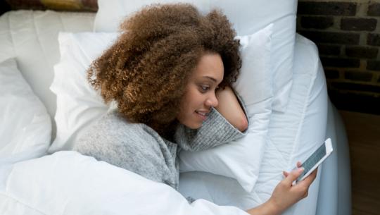 person in bed checking phone