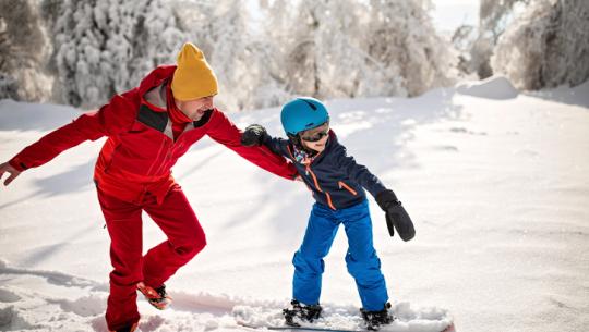 man and child snowboarding