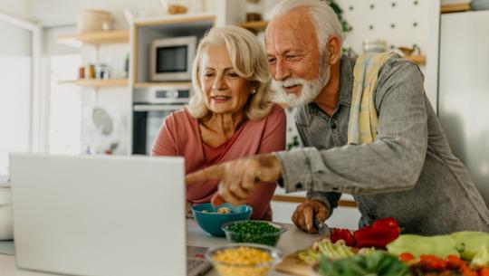 couple cooking, looking at computer