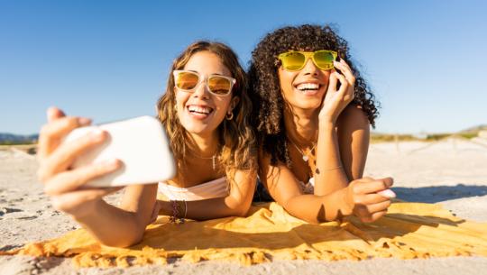 two women at beach taking selfie