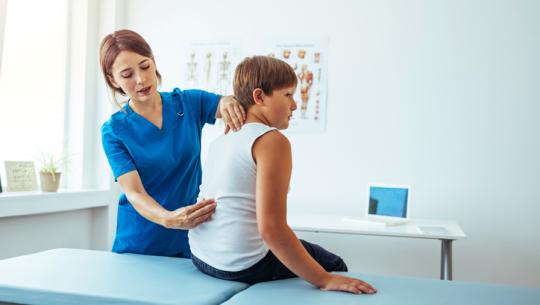healthcare professional looking at young boy's back