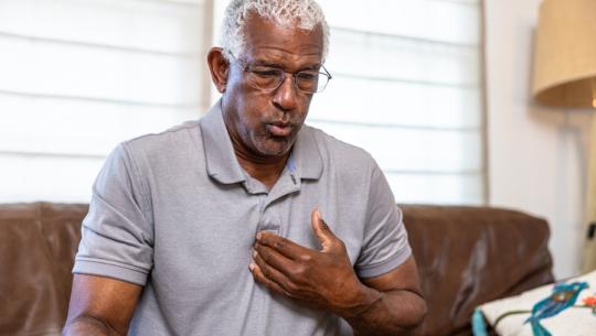 man on couch pointing to chest