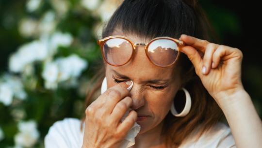 woman rubbing eye with tissue