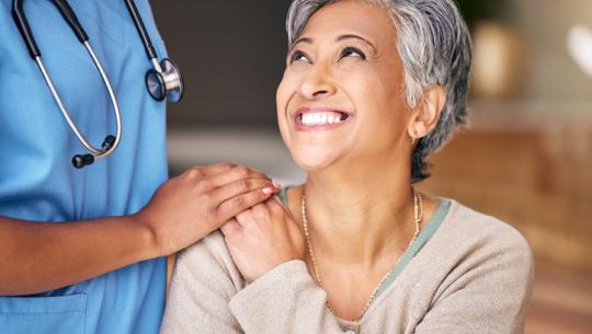 health care professional putting hand on woman smiling