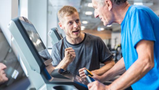 Man encouraging man on treadmill