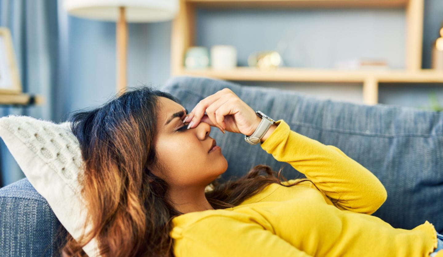 woman laying down on couch with head pain