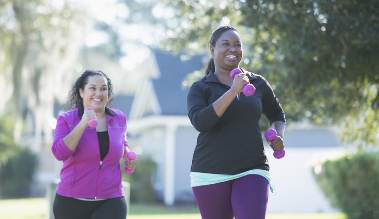 two woman exercising out with hand weights