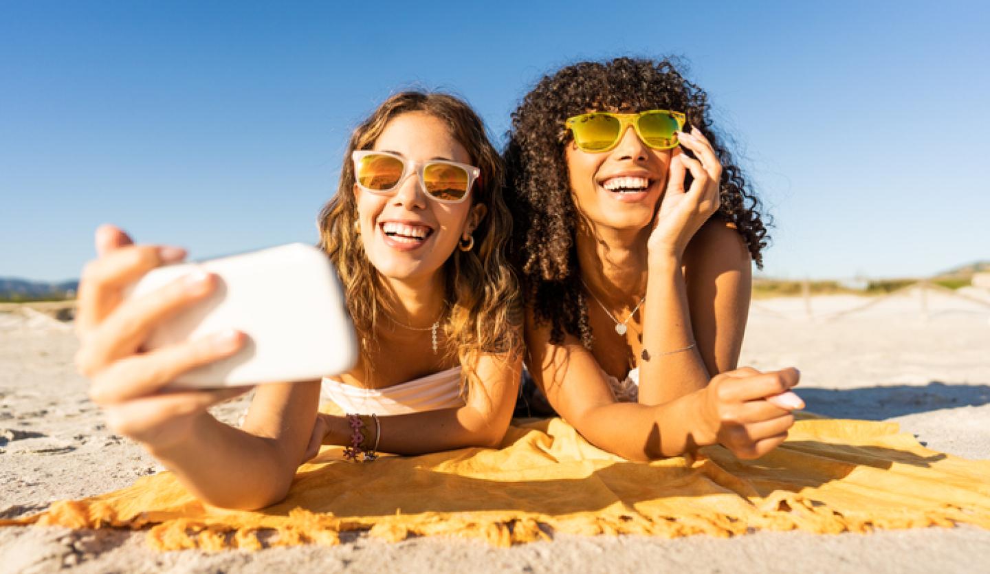 two women at beach taking selfie