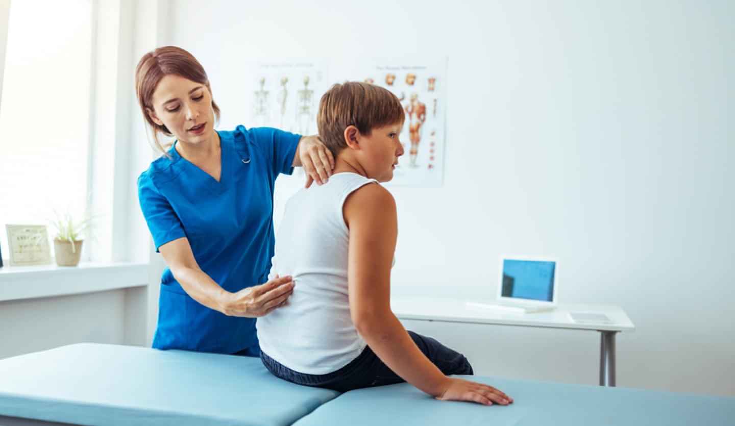 healthcare professional looking at young boy's back