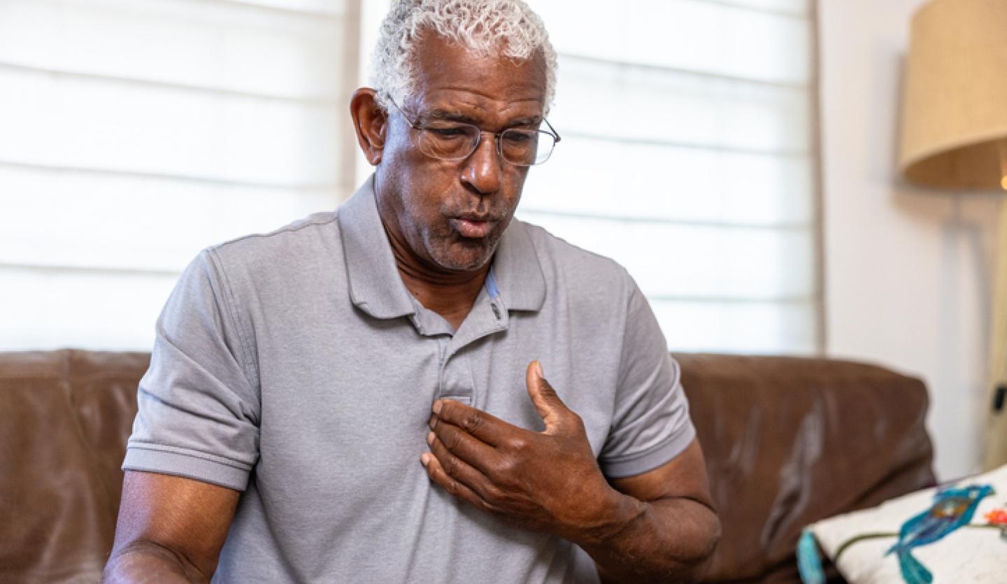 man on couch pointing to chest