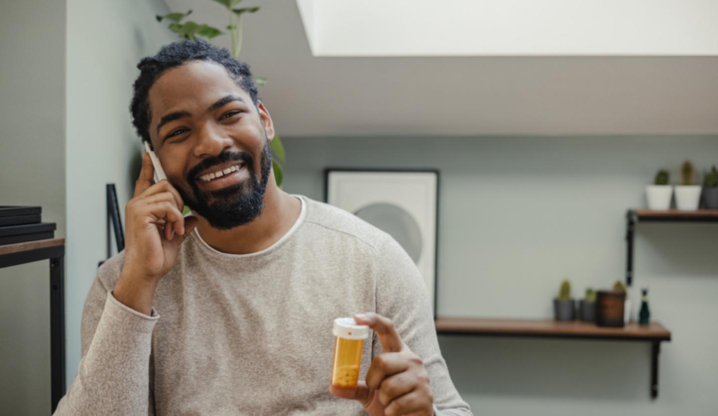 man on phone holding pill bottle