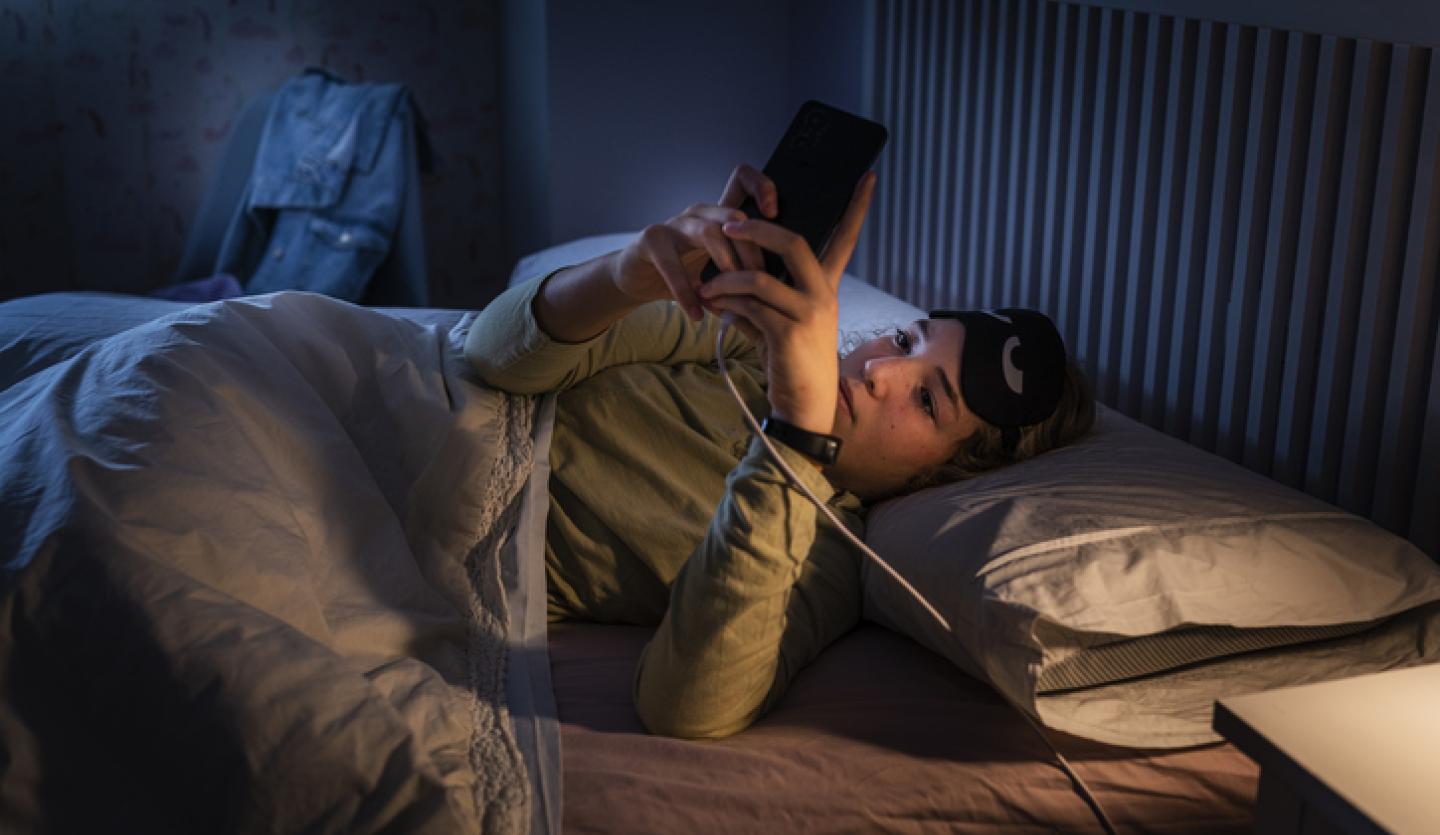 young woman looking at cell phone in bed