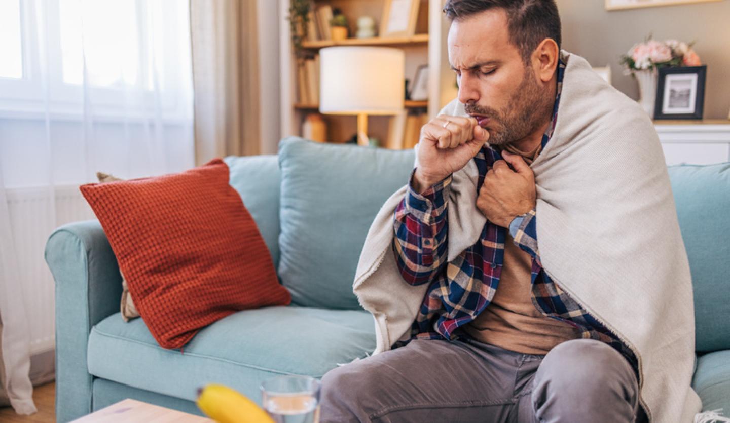 man coughing on couch