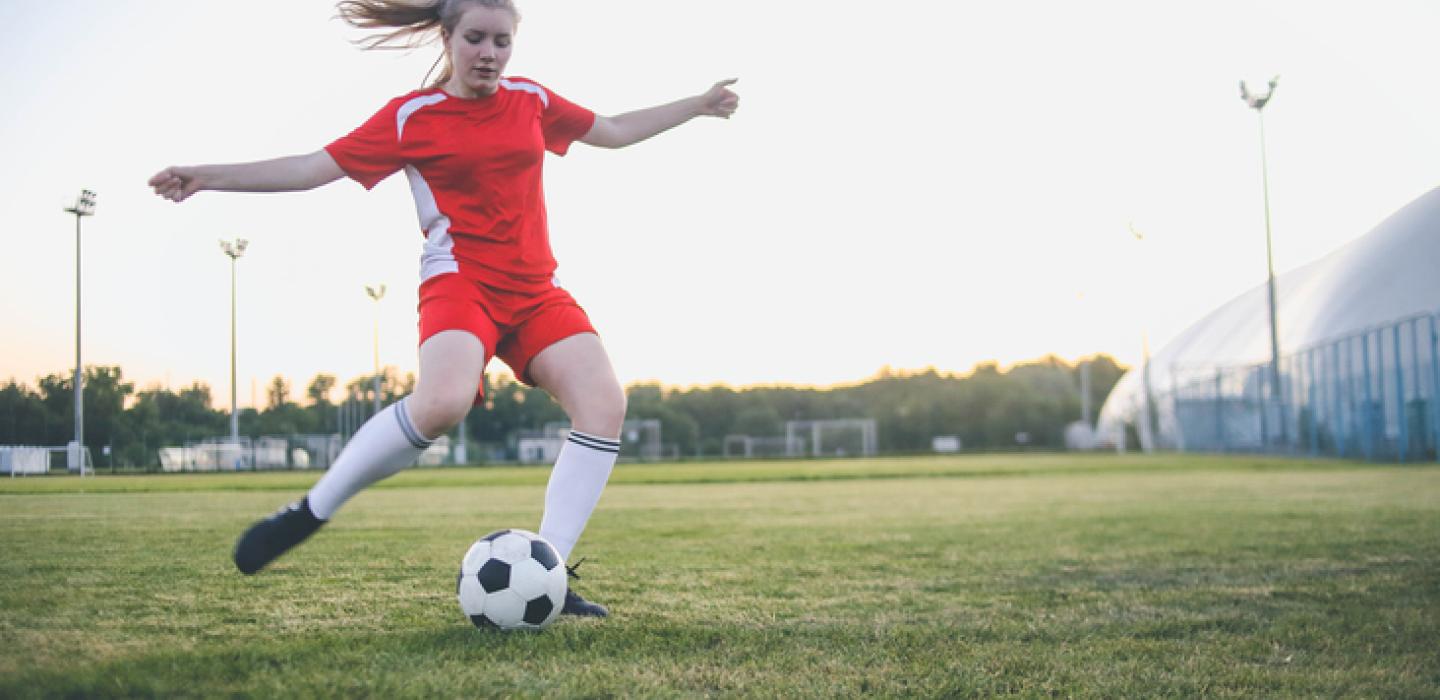 young woman playing soccer on field