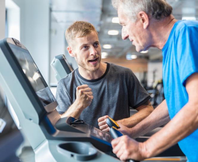 Man encouraging man on treadmill