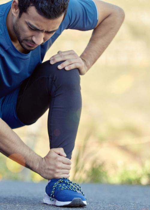 man kneeling and holding ankle