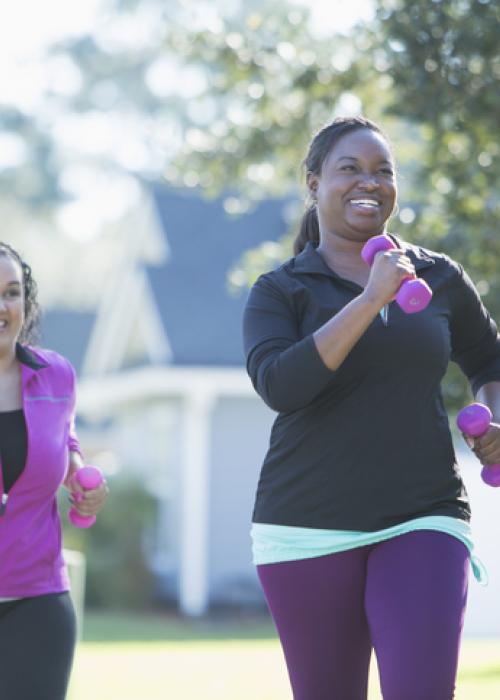 two woman exercising out with hand weights