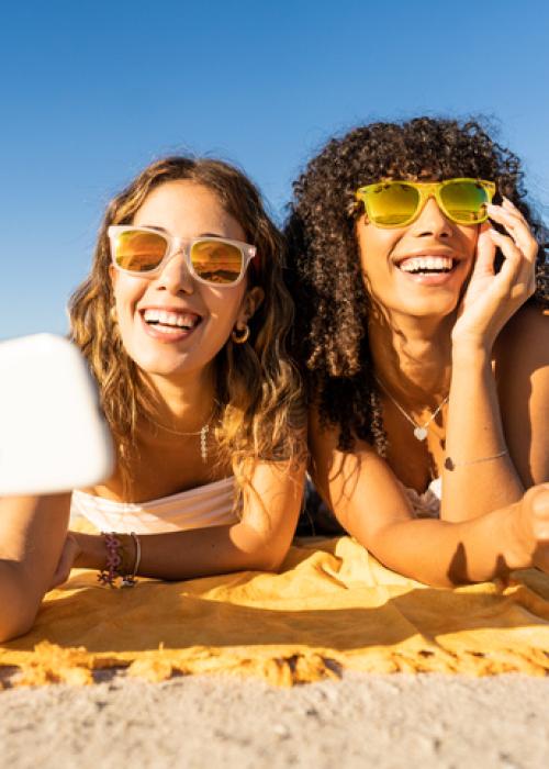 two women at beach taking selfie