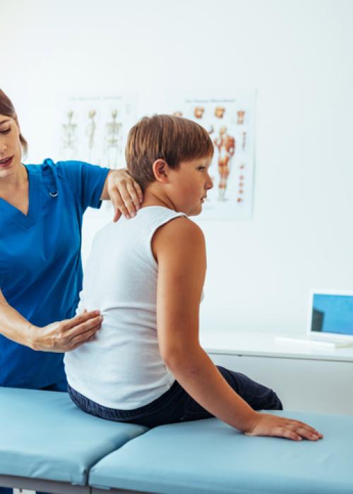 healthcare professional looking at young boy's back