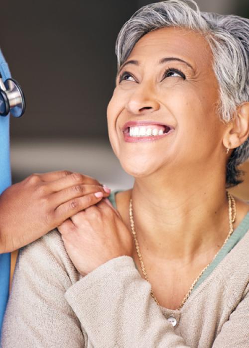 health care professional putting hand on woman smiling