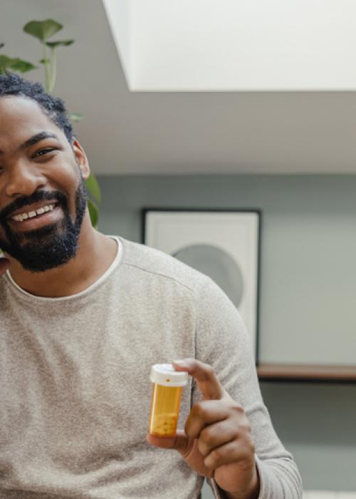 man on phone holding pill bottle