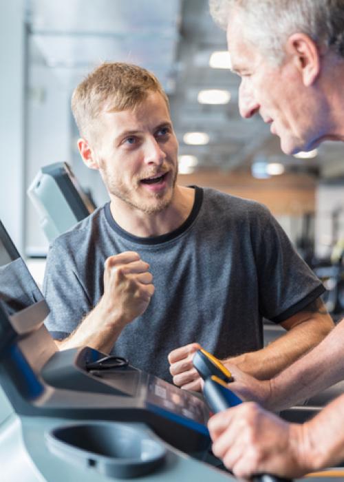 Man encouraging man on treadmill