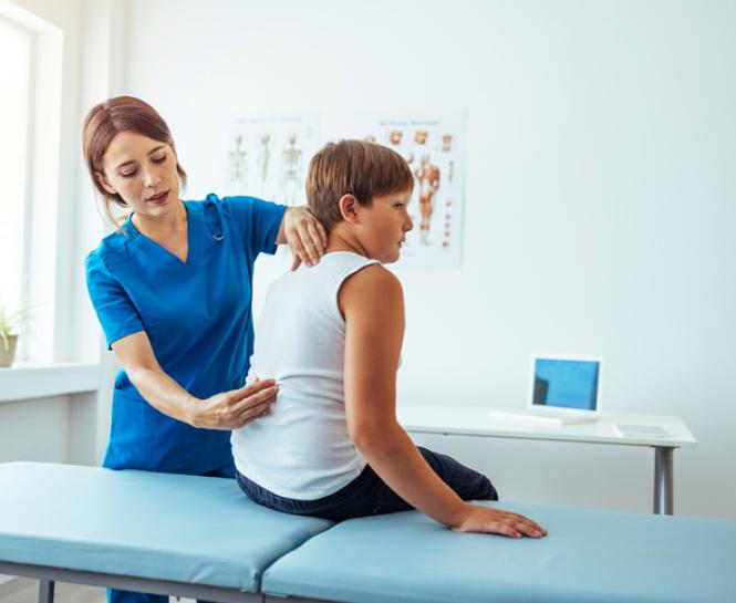 healthcare professional looking at young boy's back